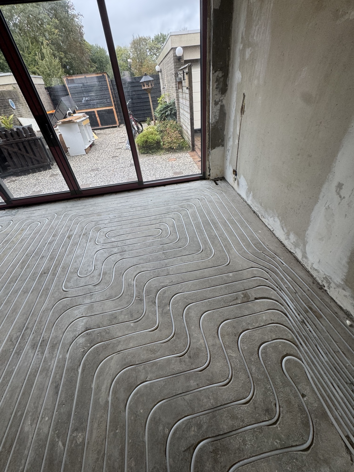 Vloerverwarming ingefreesd in de zandcementvloer bij de achterpui in Arnhem
